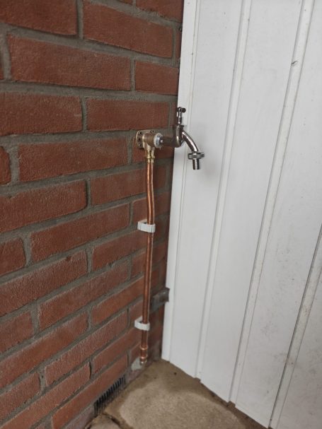 Kraan op een muur met een koppeling aan een stenen oppervlak.